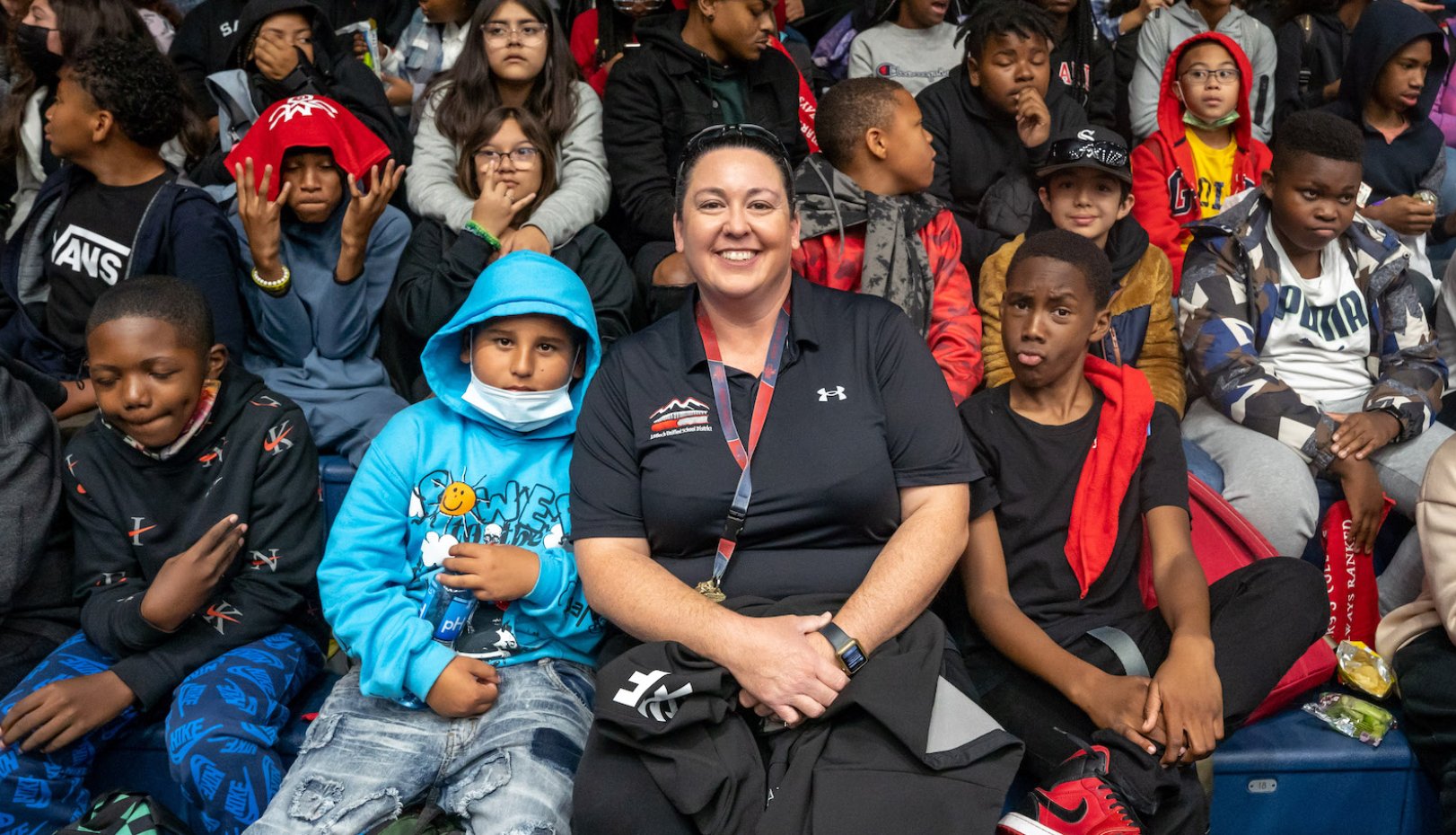 Lindsay Lopez-Wisely '04 sits amongst middle school students at a basketball game