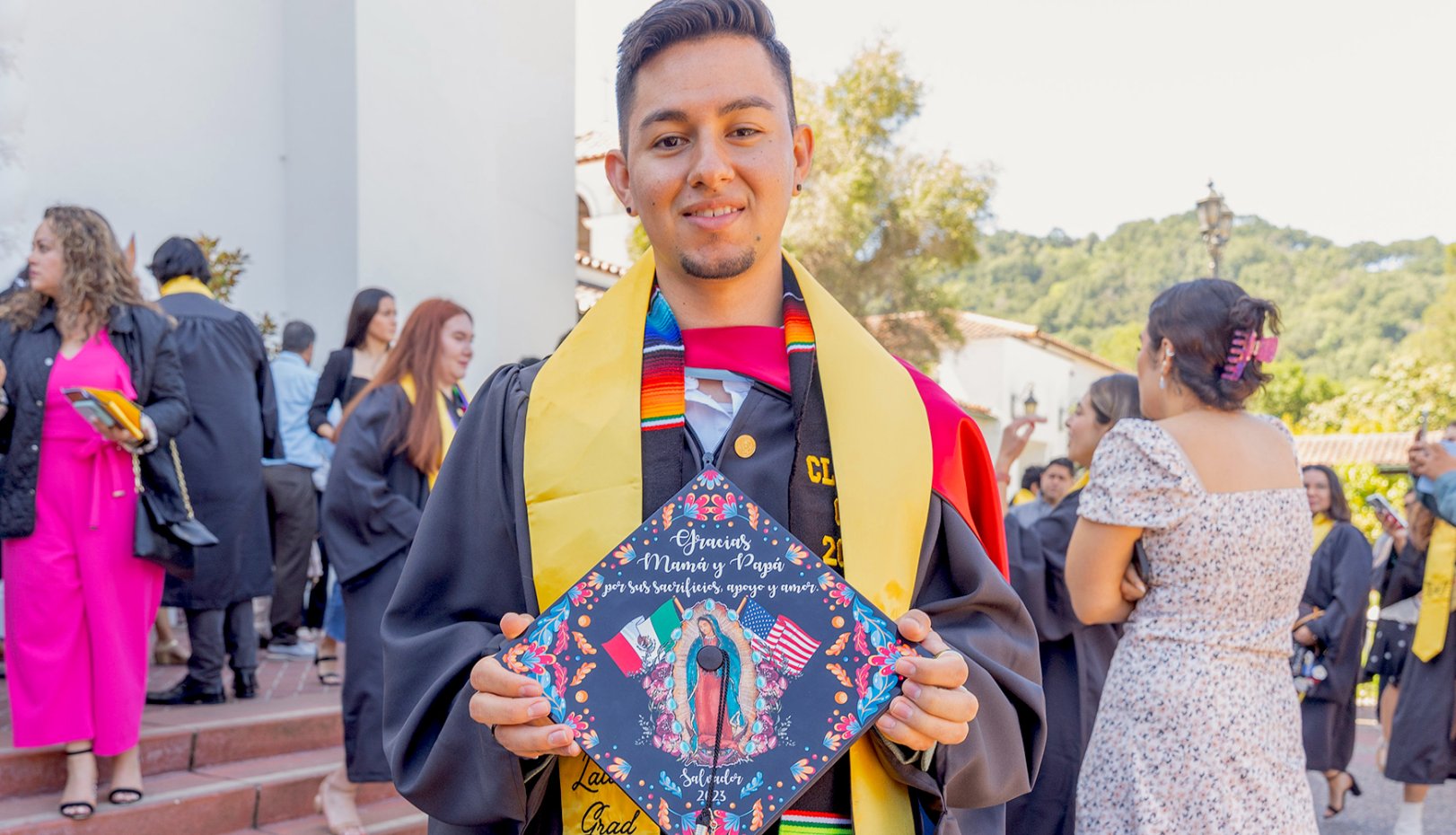 Student holding mortarboard with image of Virgen de Guadalupe at Latinx Graduate Celebration 2023