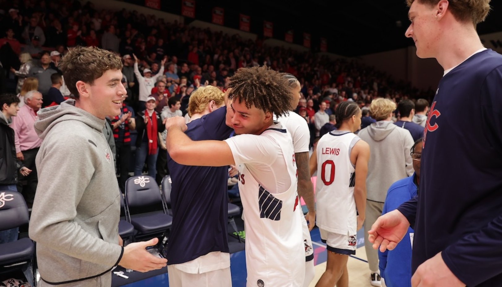 Men's basketball player Jordan Ross hugs a teammate