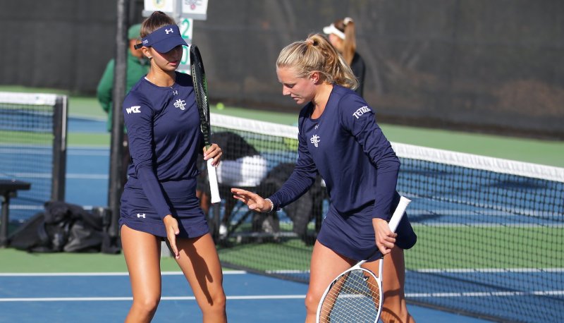 Two women's tennis players high-five on the court