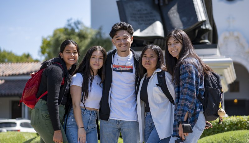 Five Saint Mary's students in front of statue of John Baptist de la Salle