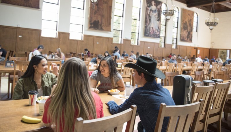 Four students sit at a long dining table in Oliver Hall