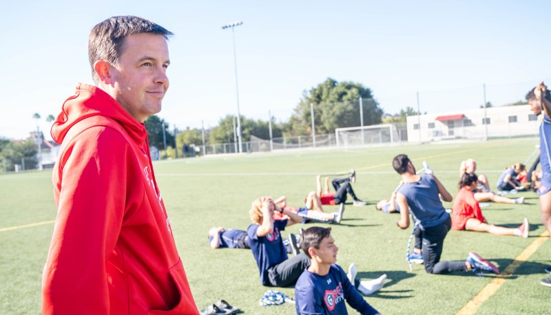 Marty Kinsey at practice, while student-athletes stretch