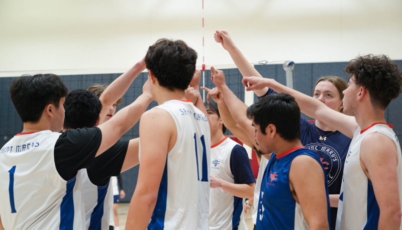 Men's Volleyball huddle together for a game cheer
