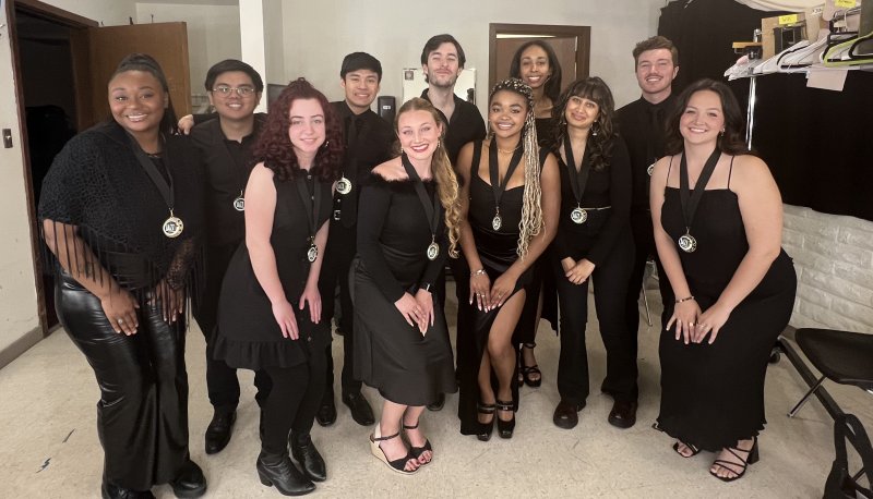 SMC Jazz Singers dressed in black pose in a room at the CA Jazz Competition with medals around their necks.