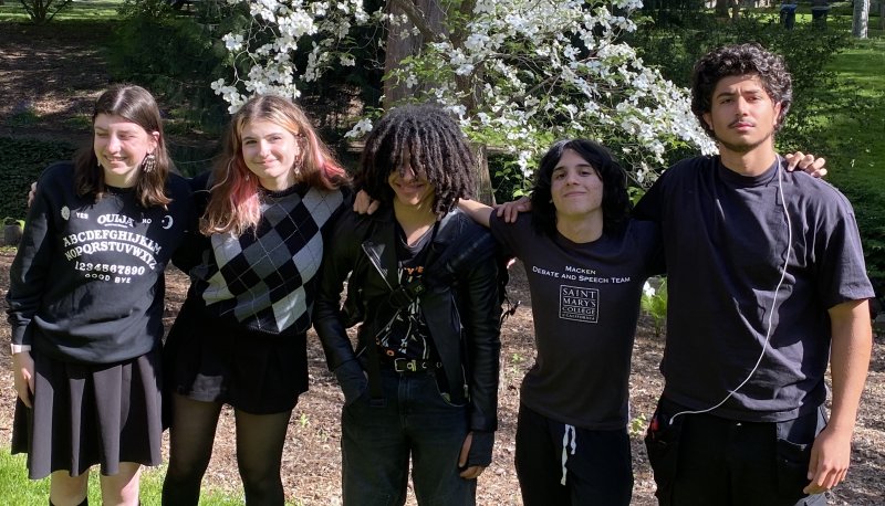 Five SMC students stand in front of a tree in bloom. They are all wearing black or dark colors.