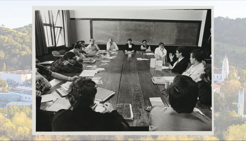 Fr. Owen Carroll, right, leading a discussion around seminar table; campus image screened behind old photo.