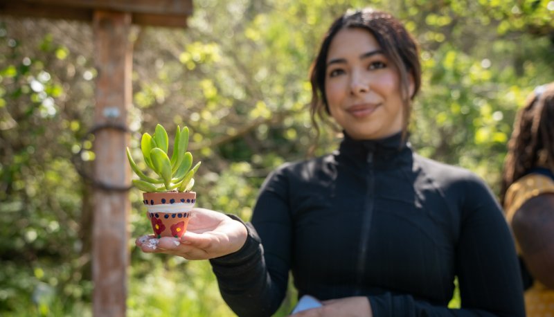 Student holding a succulent in a pot on Earth Day 2024