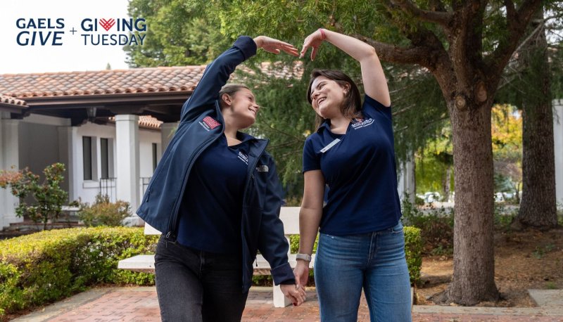 Two students shape their arms into a heart shape, signifying we love our donors!