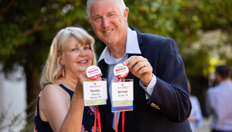 Roselle and Mike Nerney hold up their nametags with buttons reading "I met my spouse at Saint Mary's"