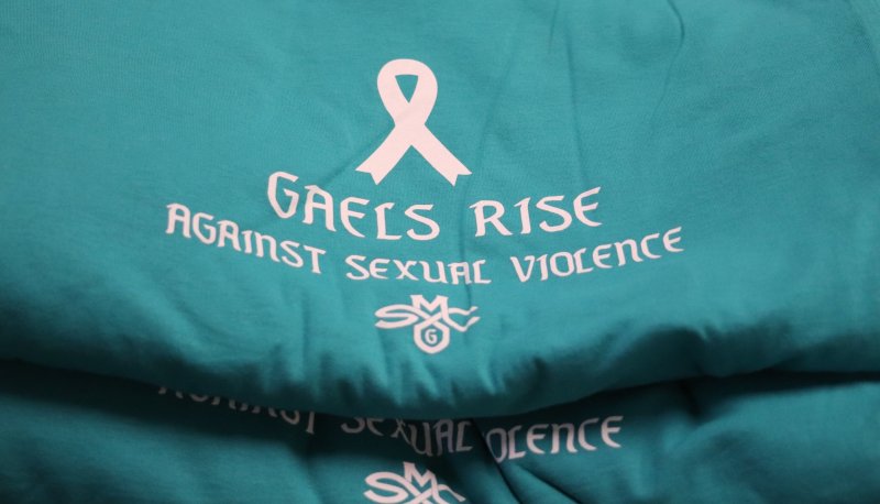 Teal T-shirts with a white ribbon and the words "Gaels Rise Against Sexual Violence"