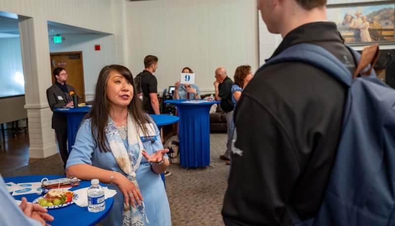 A woman speaks with a student in a conference room