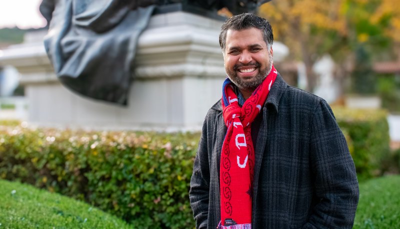 mba alum and author, Sanjay Trivedi smiling on Saint Mary's campus at the foot of De La Salle