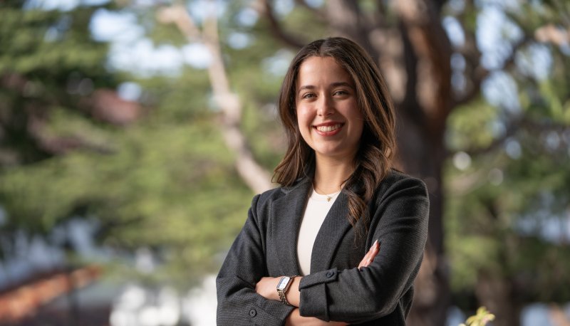 Alejandra Perez '26 in a blazer posing in front of a tree on campus