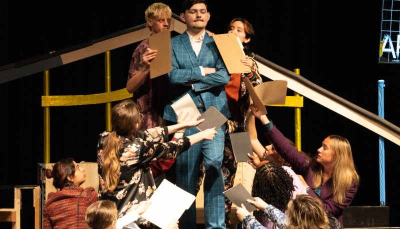 Rehearsal photo of PIPPIN with actors all crowded around King Charles.