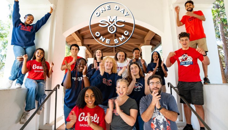 Students cheer and clap in an outdoor arcadeway; logo reads: One Day One SMC
