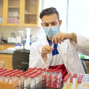 1 male lab student working with samples in vials in a lab