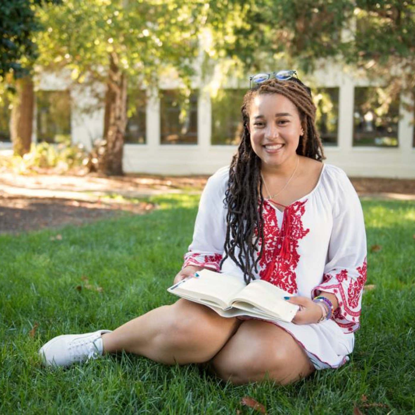 Student sitting on grass with book open