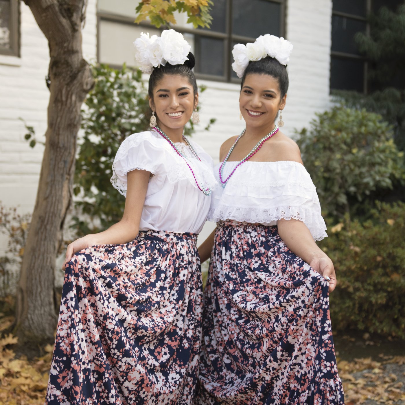two women in ballet folklorico stand and pose in costumes
