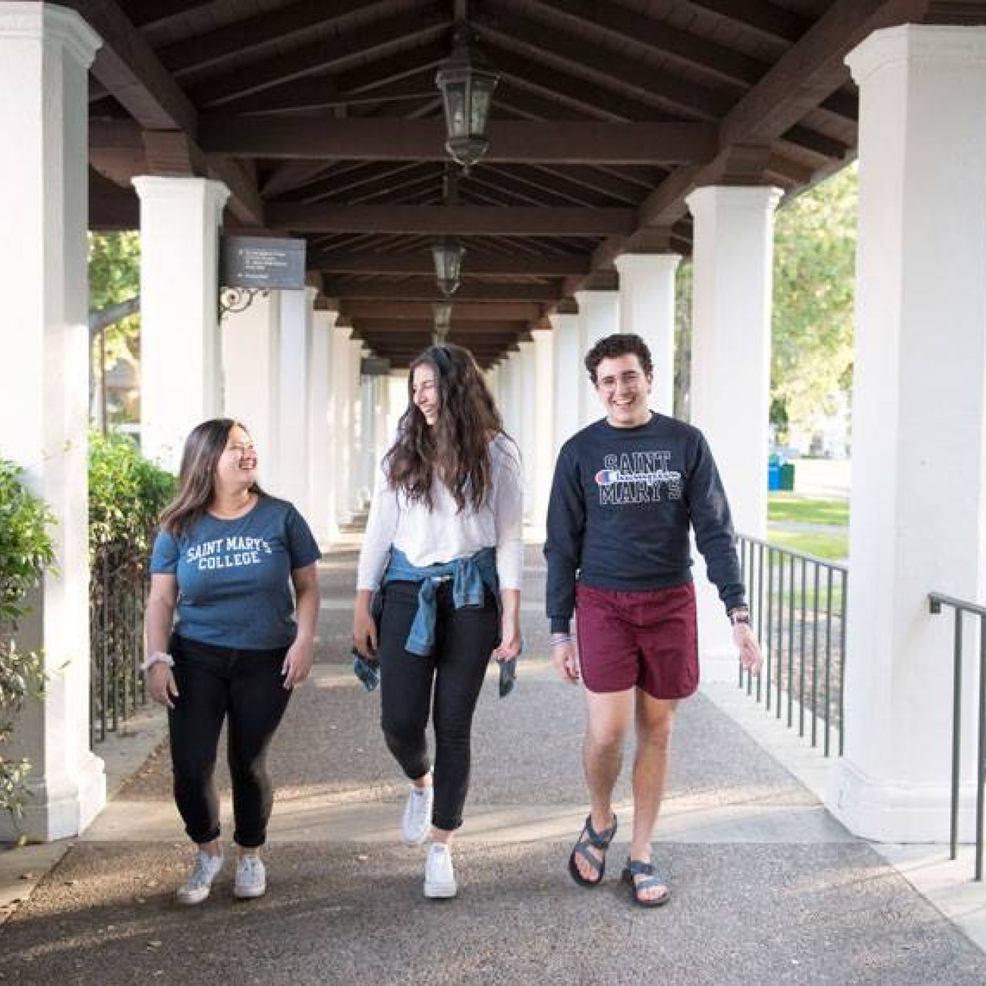 Three students walking in a covered walkway talking
