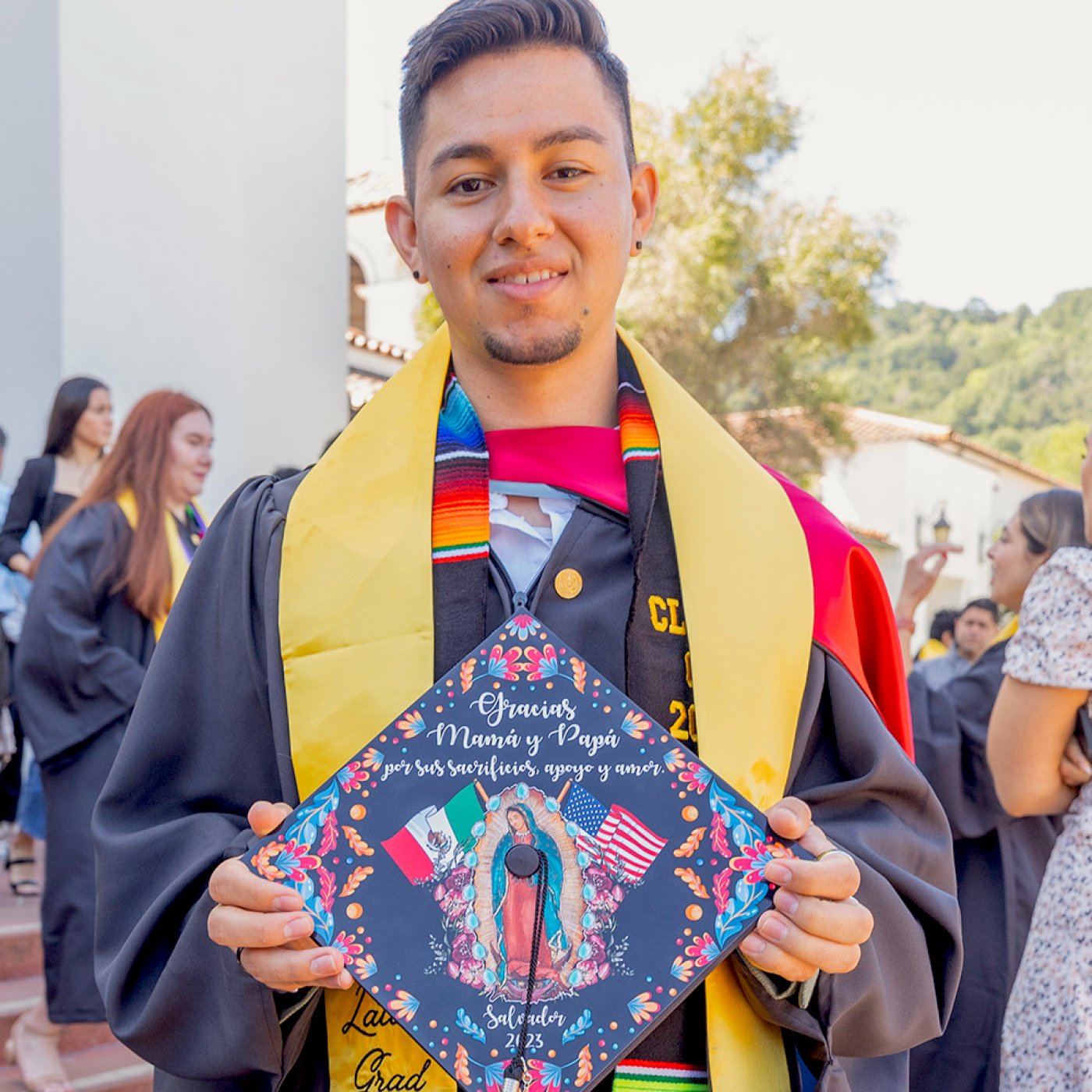 Student holding mortarboard with image of Virgen de Guadalupe at Latinx Graduate Celebration 2023