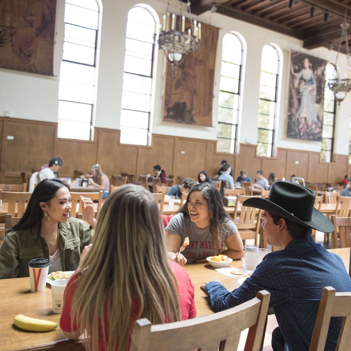 Four students sit at a long dining table in Oliver Hall