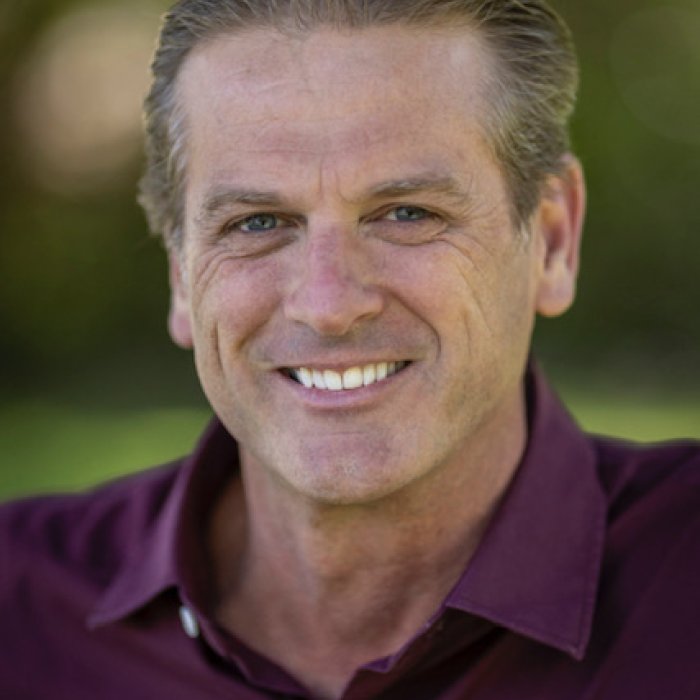 Stewart Burr in a purple polo shirt smiling at camera, against a blurred background