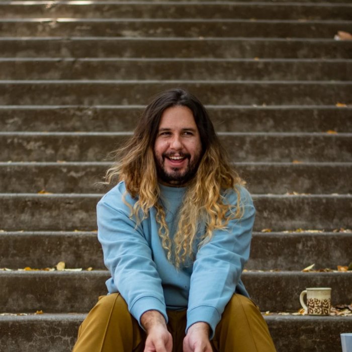 Andrew Merrell sitting at the bottom of stairs, smiling and looking to the right