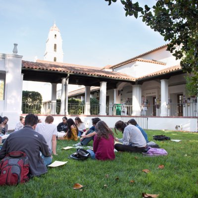 A class meeting outside on the grass with the SMC chapel in the background