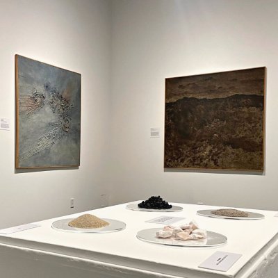 Installation image of From the Ground Up showing paintings and earth materials of asphalt, gypsum and sand. 