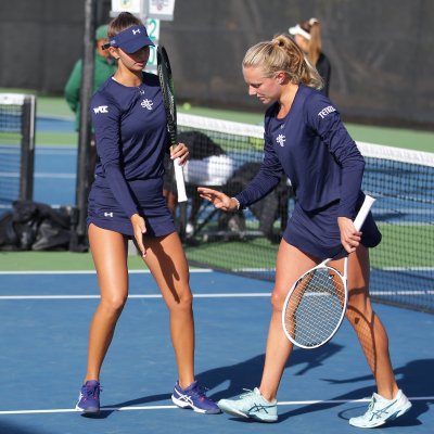 Two women's tennis players high-five on the court