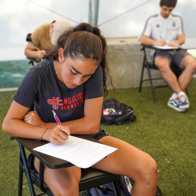 student writing on paper sitting in desk