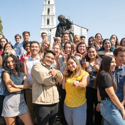 Students in a group smiling in front of the saint mary's college campus