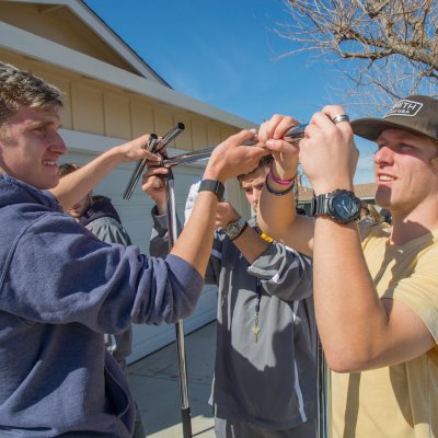 Three male students helping assemble housewares as part of a service project for hurricane relief in 2020