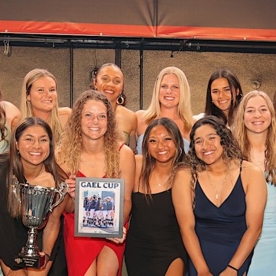 Women's softball team posing with Gael Cup award beneath Saint Mary's College banner, awards ceremony May 2024
