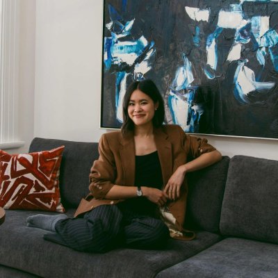 Sierra Nguyen sits on a sofa with a large, blue painting behind her