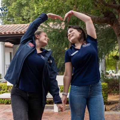 Two students shape their arms into a heart shape, signifying we love our donors!