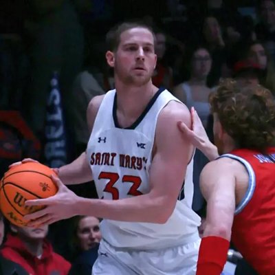 Men's Basketball player Luke Barrett holds the ball away from an LMU defender in January 2025