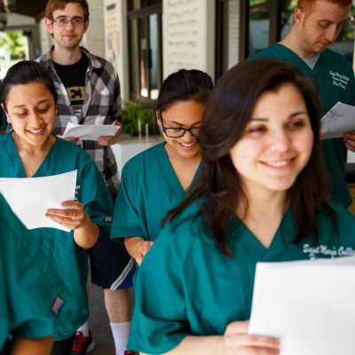 A group of Saint Mary's students wearing teal uniforms for Human Anatomy class and holding papers