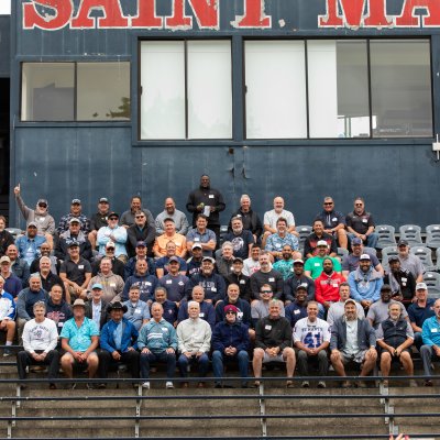 Alumni sit in the bleachers to recreate a classic team photo