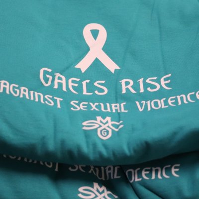 Teal T-shirts with a white ribbon and the words "Gaels Rise Against Sexual Violence"
