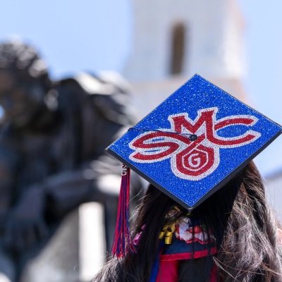 Student wearing mortarboard with SMC logo in front of chapel, May 2025