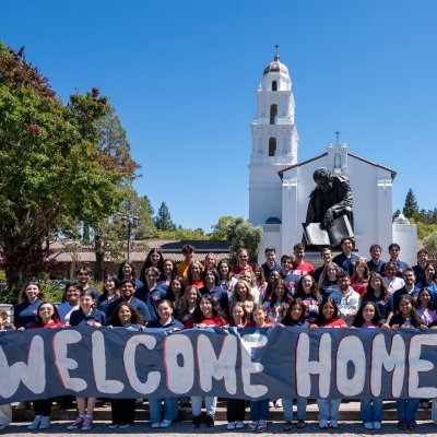 Students in front of Chapel with sign WELCOME HOME GAELS