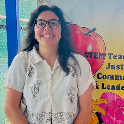 Xochilt Delgado Noyce Scholar in front of wall with mural