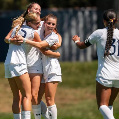 Four women's soccer players celebrate a victory in fall 2025