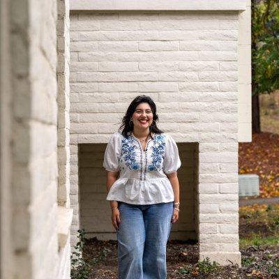 Cecilia Espinoza smiles in front of a campus building