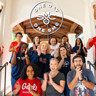 Students cheer and clap in an outdoor arcadeway; logo reads: One Day One SMC