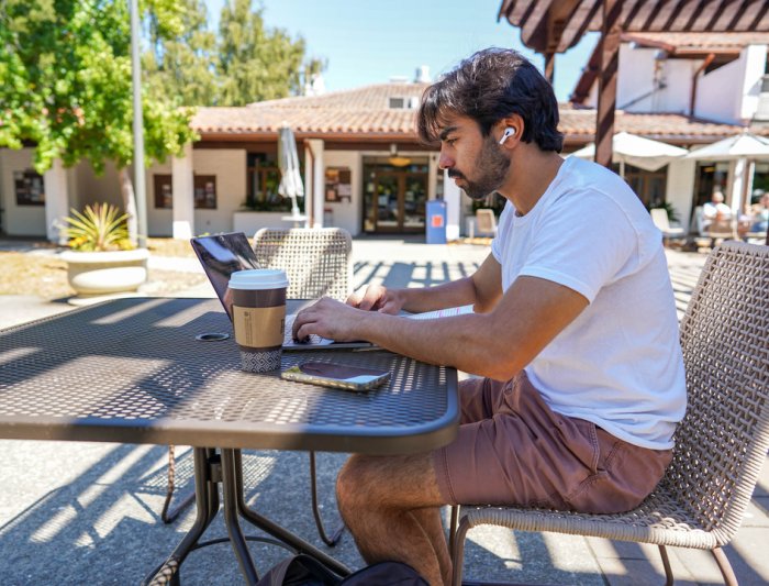 A student with working on his computer outside