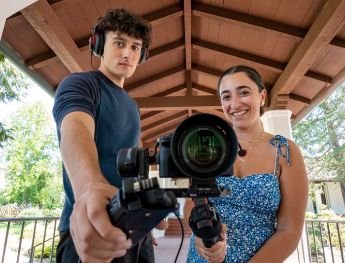 Students holding a camera and a mic toward the camera