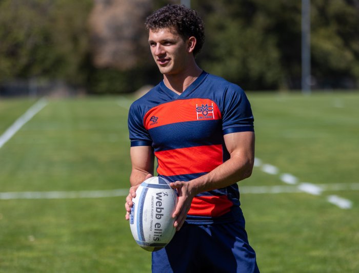 A men's rugby player is holding a ball